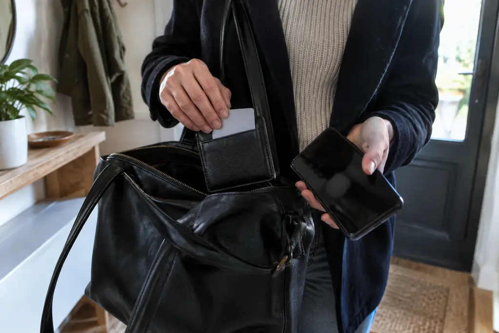 Une personne prend son téléphone éteint et une carte neutre avant de sortir.